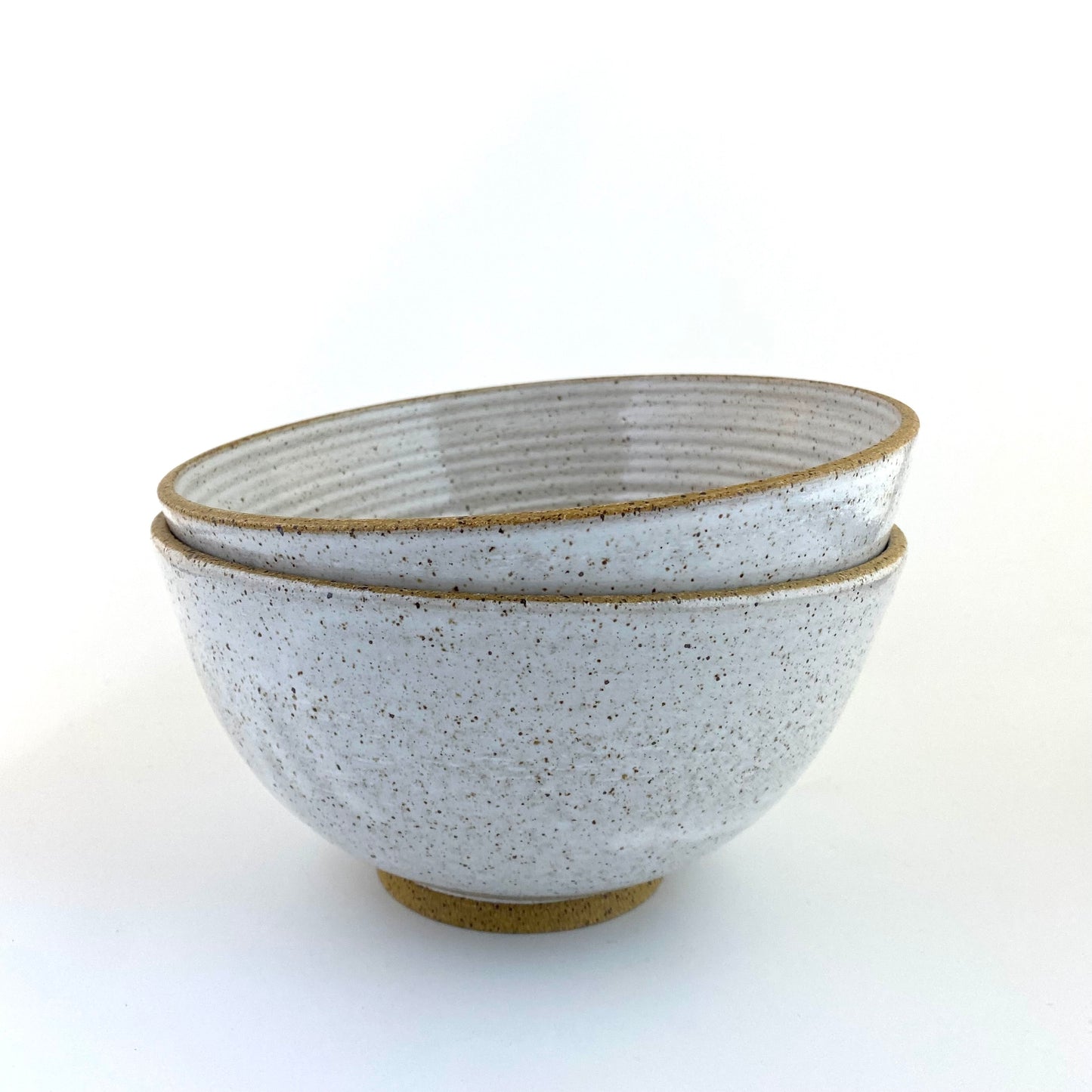 Stack of handmade ramen bowls in speckled stoneware with white glaze
